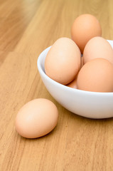 Eggs in white bowl on wooden table