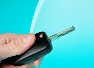 Hand holding car keys on blue background