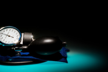 Sphygmomanometer on blue, reflective table and black background