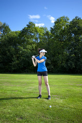 Pretty girl playing golf on grass
