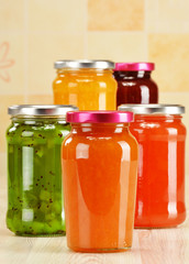 Fototapeta na wymiar Jars of fruity jams on kitchen table. Preserved fruits