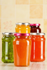 Jars of fruity jams on kitchen table. Preserved fruits