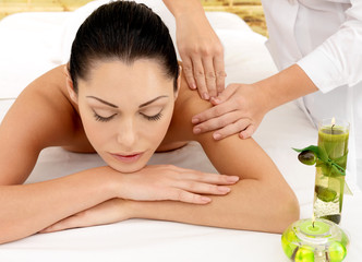 Fototapeta na wymiar Woman having massage of shoulder in spa salon