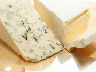 Brie and dor blue cheese on wooden desk with knife