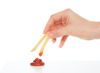 Hand dip french fries chips into ketchup