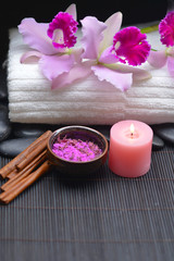 orchid on towel and stones ,candle, salt in bowl on mat