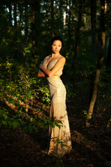 Beautiful young woman in dress in garden on sunset