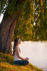 Caucasian woman practicing yoga at lake