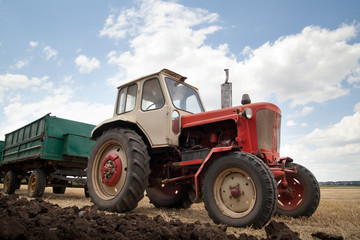old tractor in field, against a cloudy sky
