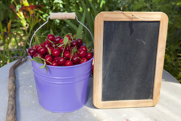 Blecheimer mit Kirschen und Schiefertafel