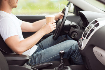 man drinking coffee while driving the car