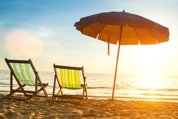 Beach loungers on deserted coast sea at sunrise