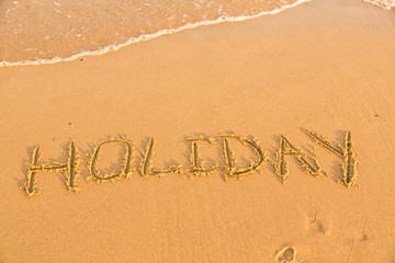 Fototapeta na wymiar Word holiday on the yellow sandy beach