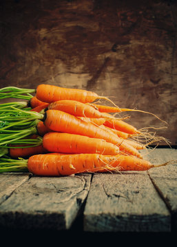 Fresh Organic Carrots lies on wooden background, rustic