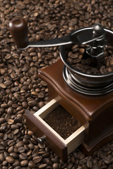 コーヒー豆の背景の上にコーヒーミル