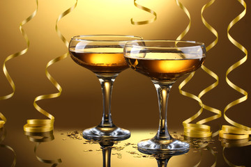 glasses of champagne and streamer on yellow background