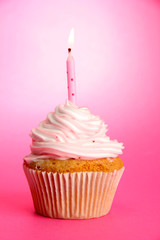 tasty birthday cupcake with candle, on pink background