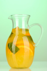 Orange lemonade in pitcher on turquoise background