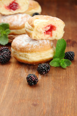Tasty donuts with berries on wooden table