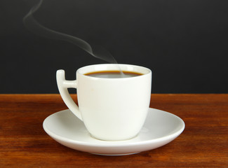 Cup of coffee on wooden table on black background
