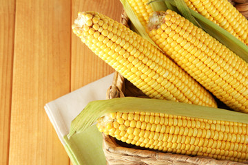 Crude corns in basket on napkin on wooden table
