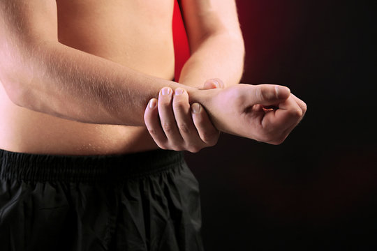 Young man with hand pain, on red background