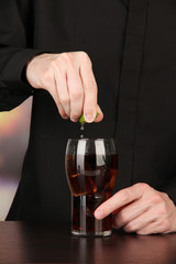 Bartender making cocktail on bright background, close-up