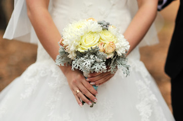 Obraz na płótnie Canvas Bride holding white wedding bouquet of roses and love flower