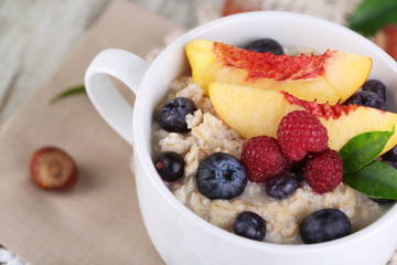 Oatmeal in cup with berries on napkins on wooden table