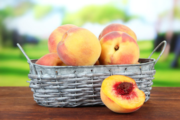 Ripe sweet peaches in wicker basket, on bright background
