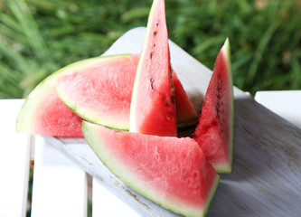 Watermelon slices on board on table on grass background