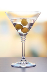 Martini with green olives on table in bar