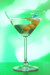 Martini with green olives on table in bar