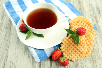 Cup of tea with cookies and strawberries on table close-up