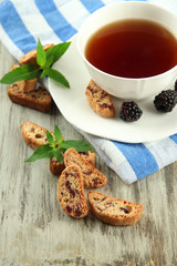 Cup of tea with cookies and blackberry on table close-up