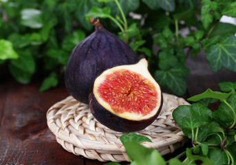 Ripe figs in leaves on wooden table close-up