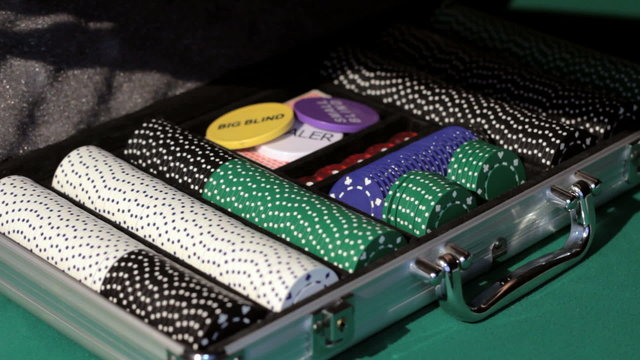 Hands open the aluminium suitcase with poker set.