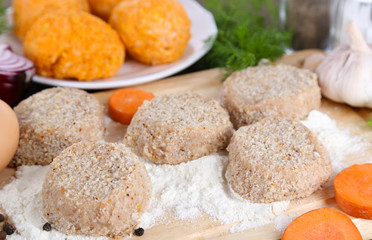 Meat patties on board and on plate on wooden table