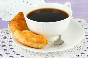 Tasty croissants and cup of coffee on table close-up