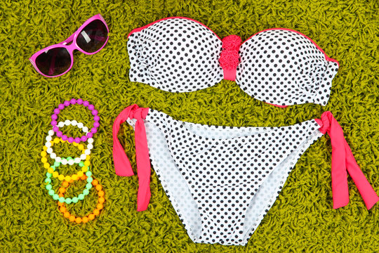 Swimsuit and beach items on green background
