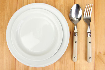 Plate and cutlery on wooden table close-up