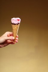 Berry icecream cone in hand on brown