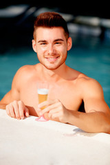 Handsome man in the pool toasting with champagne