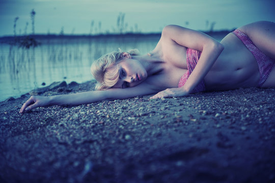 Tired blonde girl lying on the beach