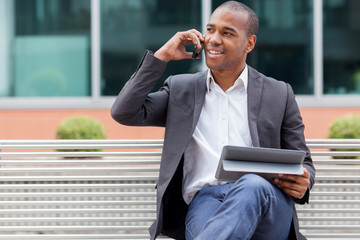 Afro American manager sitting on the bench and phoning