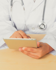 Asain female doctor diagnoses by using tablet.