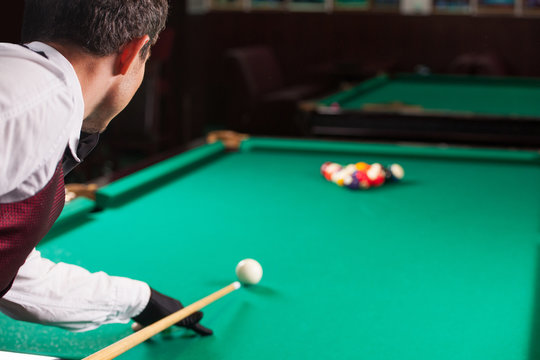 Playing pool. Rear view of man aiming the billiard ball with cue