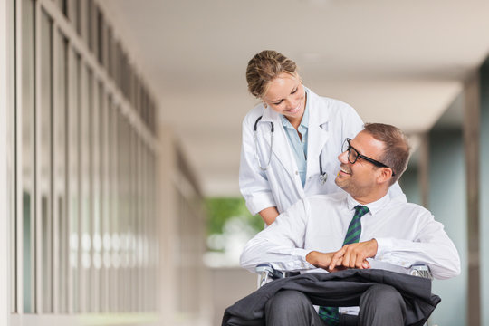 Doctor is pushing businessman on wheelchair
