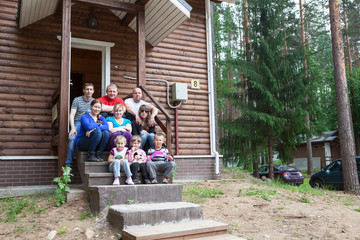 Fototapeta na wymiar Large family with nine people sitting on house porch together