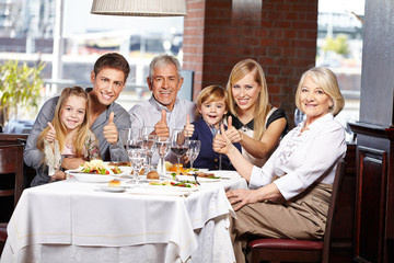 Familie im Restaurant hält Daumen hoch